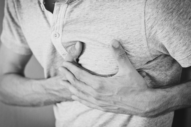 man holding his chest showing the signs of clogged arteries